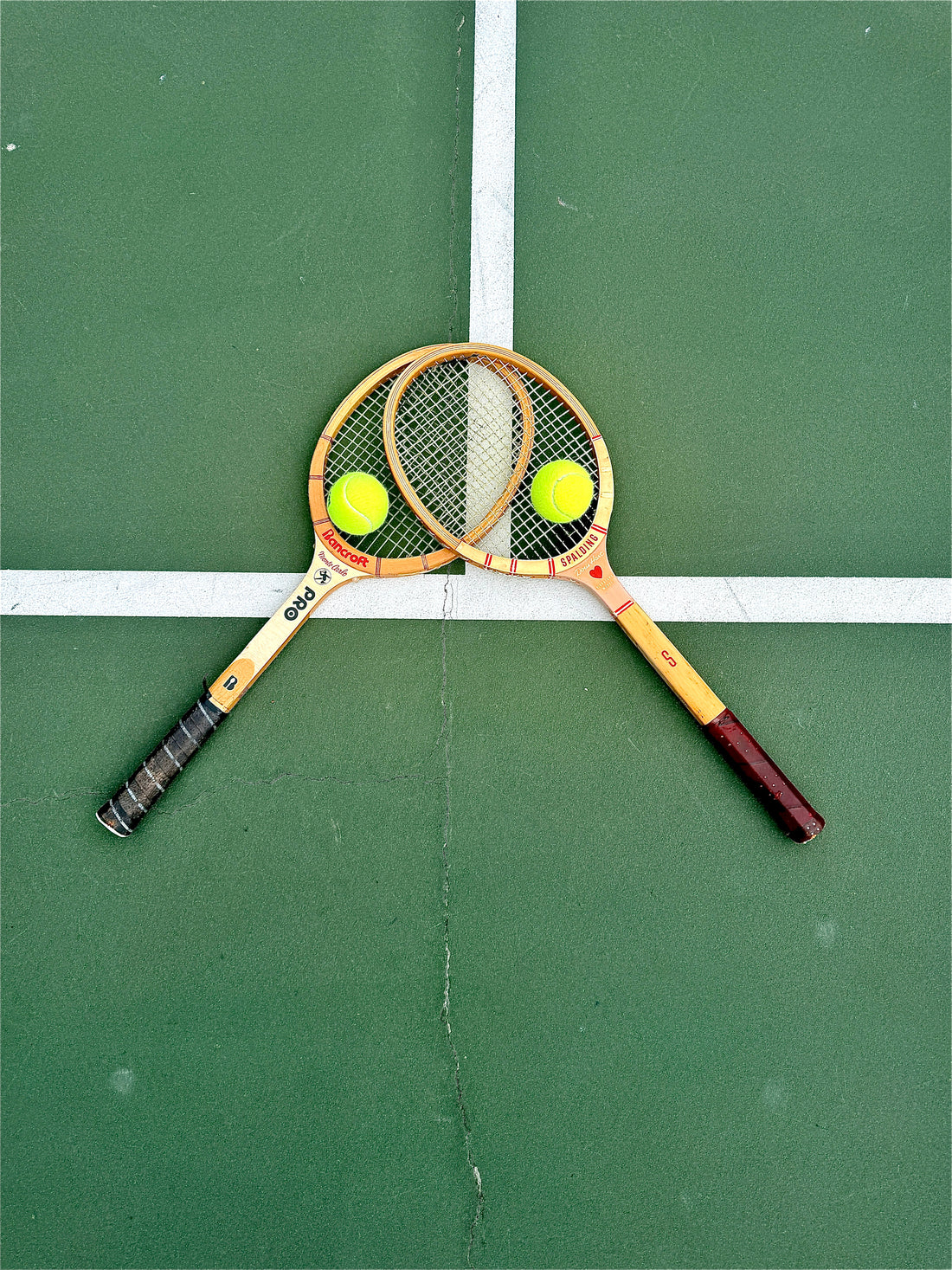 Two crossed wooden tennis racquets and tennis balls on a hard court — Court Paradise tennis slang glossary