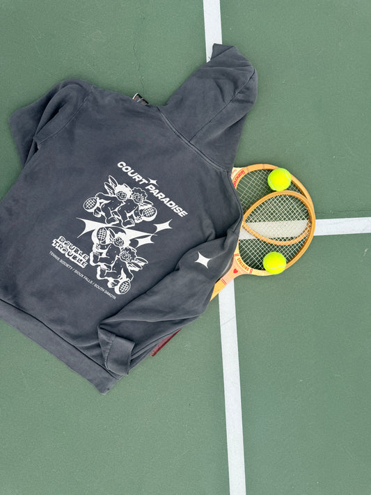 Double Trouble Hoodie in Charcoal on a green hard court, cherub back print, with a wooden racquet and tennis balls